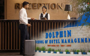 A warm welcome at the reception desk of a hotel, showcasing a hospitality professional interacting with a guest. The image also highlights the Dolphin School of Hotel Management, emphasizing its role in providing top-notch training for future leaders in the hospitality industry. The school’s reputation and dedication to excellence are symbolized by its prominent display, inviting students to pursue careers in hotel management.